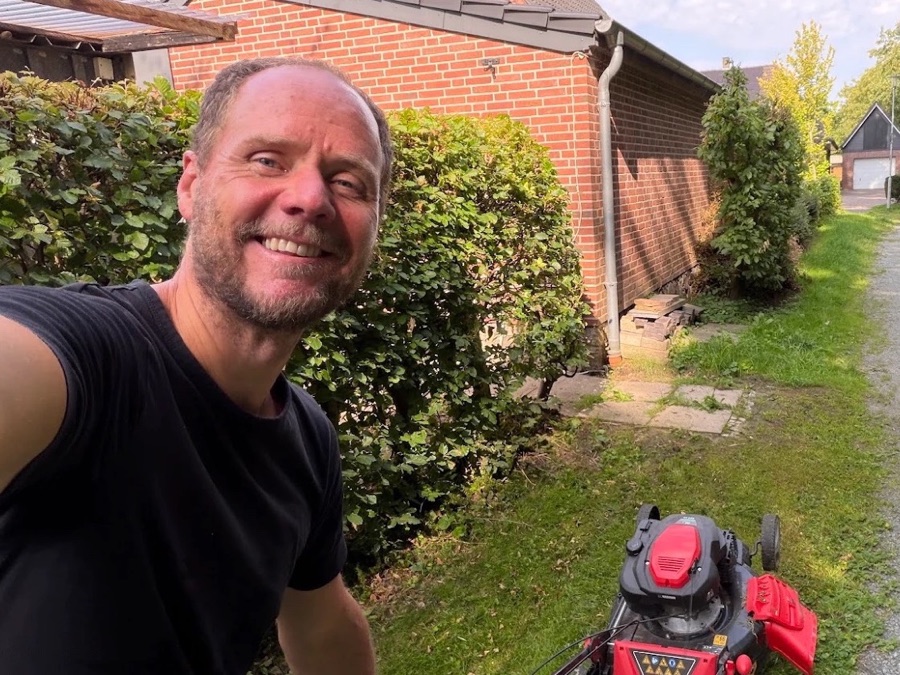 Meik Glindemann beim Rasenmähen vor einem Haus